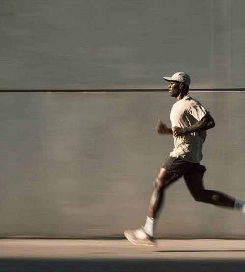 A man running past a wall in warm light